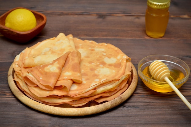 Una pila di pancake appena sfornati e una ciotola di miele accanto