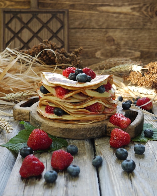 Una pila di pancake con fragole e mirtilli.