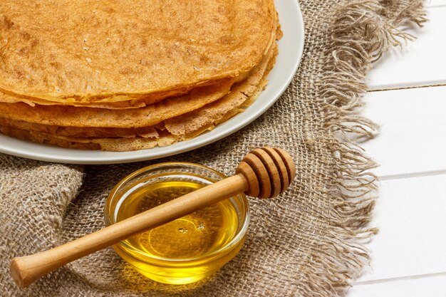 Una pila di pancake, miele, per la celebrazione del carnevale. Pancake sottili per colazione