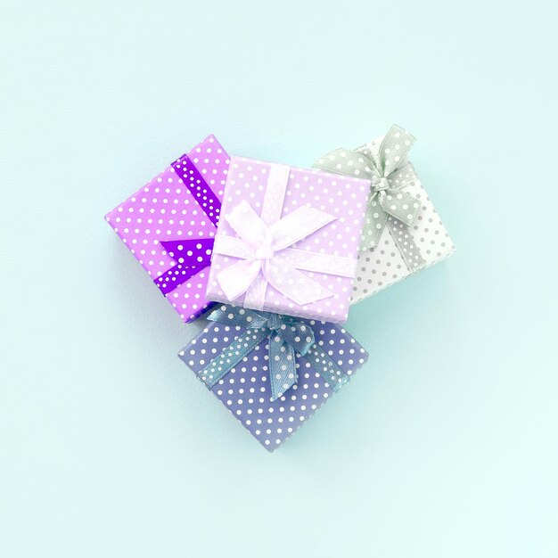Una pila di piccole scatole regalo colorate con nastri giace su uno sfondo viola minimalismo piatto