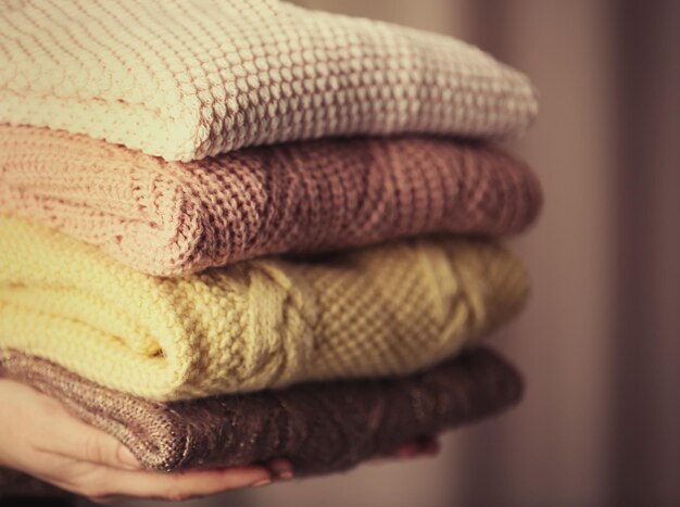 Una pila di vestiti a maglia in mani femminili in primo piano