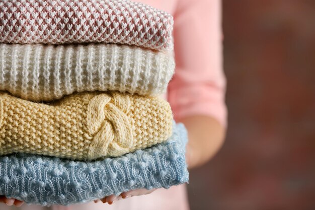 Una pila di vestiti a maglia in mani femminili in primo piano