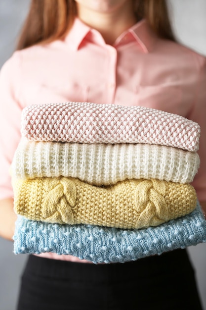 Una pila di vestiti a maglia nelle mani femminili in primo piano