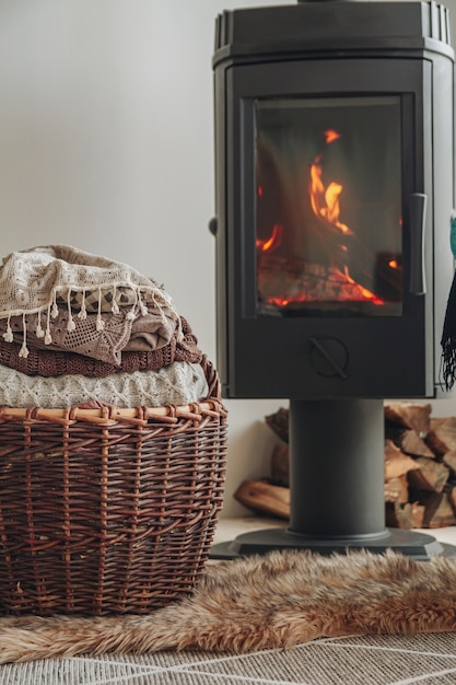 Una pila di vestiti caldi in un cesto di vimini un caminetto in ferro wit