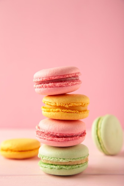 Una pila verticale di tre macarons su sfondo rosa Dessert dolce