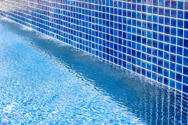 Una piscina blu con una parete piastrellata lungo la quale scorre l'acqua Riposo e relax