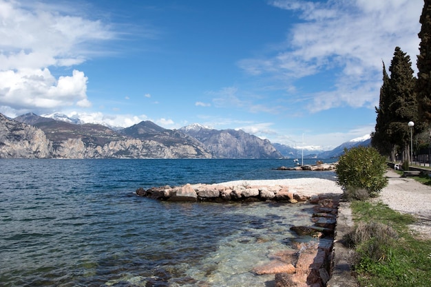 Una pittoresca costa marittima con acqua limpida e un molo di pietra sullo sfondo ci sono piccole montagne