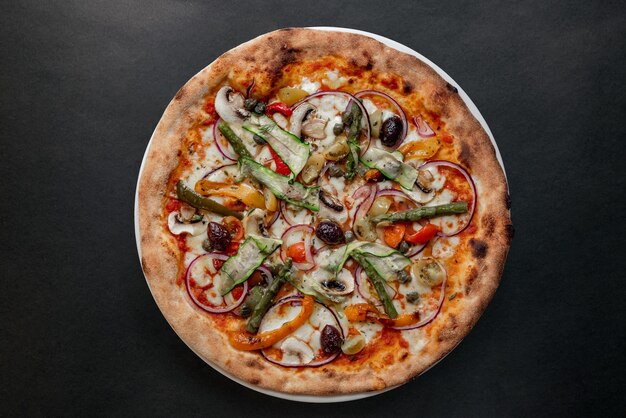 Una pizza con asparagi, asparagi e cipolle rosse su un piatto.