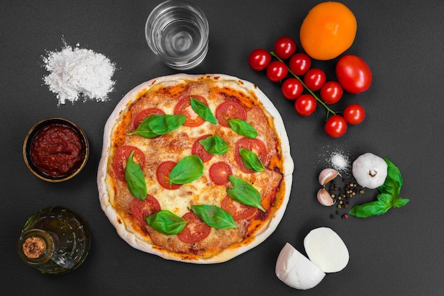 Una pizza con peperoni si trova su un tavolo accanto ad altri ingredienti.