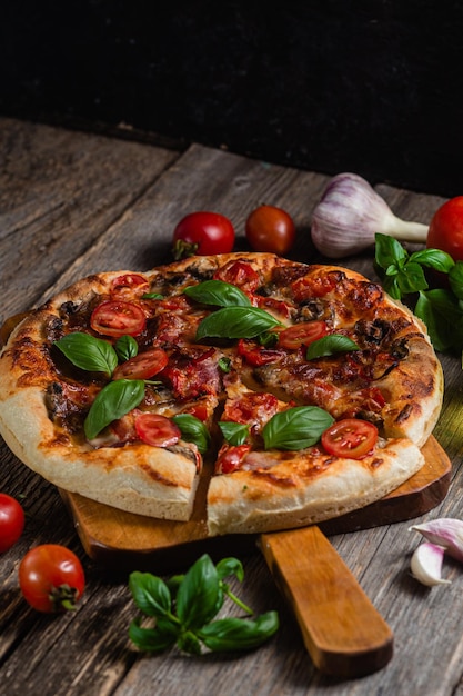 Una pizza con pomodori e basilico su una tavola di legno