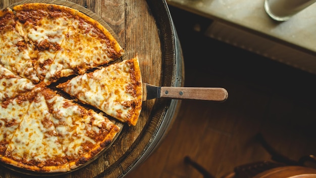 Una pizza su un vassoio di legno con un manico di legno e un manico di legno con su scritto pizza.