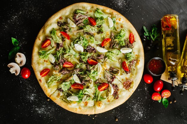 Una pizza vegetariana con verdure ed erbe aromatiche su sfondo nero