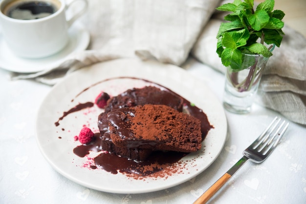 Una porzione di biscotto al cioccolato sotto la ganache al cioccolato e cosparsa di cacao in polvere al cioccolato