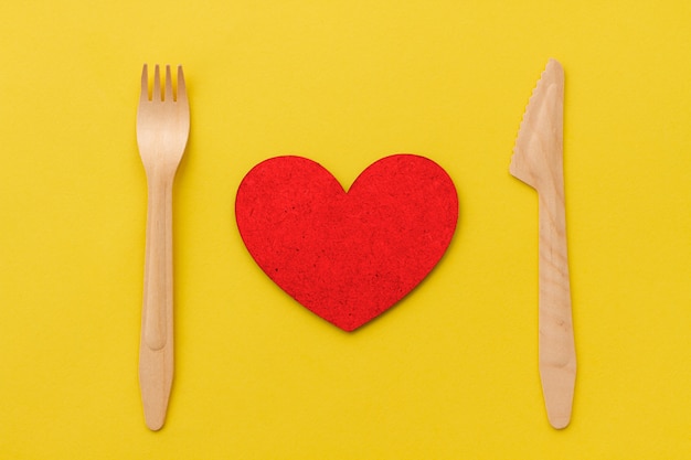 Una porzione di cuore rosso con una forchetta di legno e un coltello di legno. Amo il concetto di ristorante.