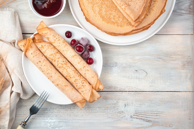 Una porzione di pancake arrotolata in tubi con bacche congelate su una superficie leggera. Vista dall'alto, con spazio per copiare. Il concetto di cucina.