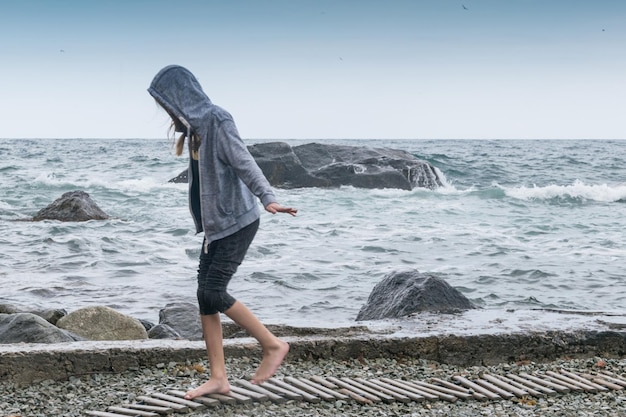 Una ragazza adolescente in un maglione su un mare freddo in tempesta Riposa sul mare l'oceano in caso di maltempo