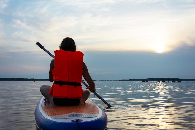 Una ragazza adolescente nuota su una tavola da sup una bella ragazza cavalca una tavola con una pagaia su un bellissimo lago