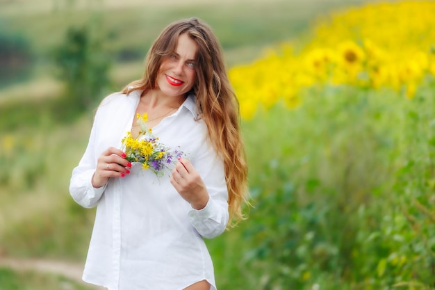Una ragazza affascinante con un bouquet di fiori selvatici Foto tenera estiva