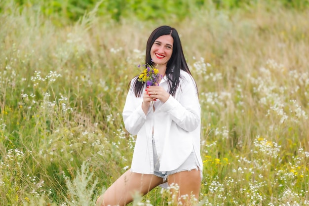 Una ragazza affascinante con un bouquet di fiori selvatici Foto tenera estiva