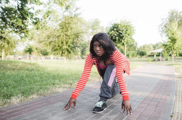 Una ragazza afroamericana si sta preparando per una corsa. posizione bassa per iniziare.