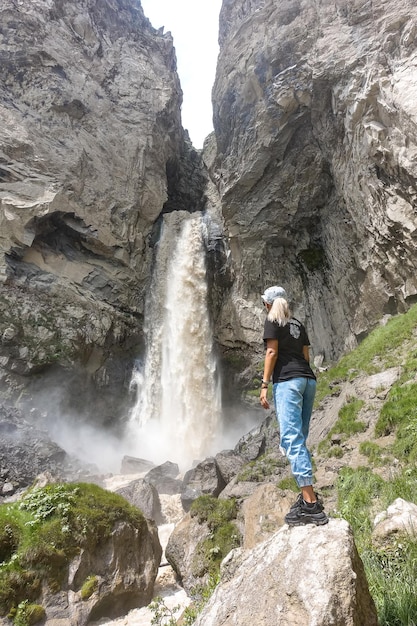 Una ragazza alla cascata Sultansu circondata dalle montagne del Caucaso vicino a Elbrus Jilysu Russia