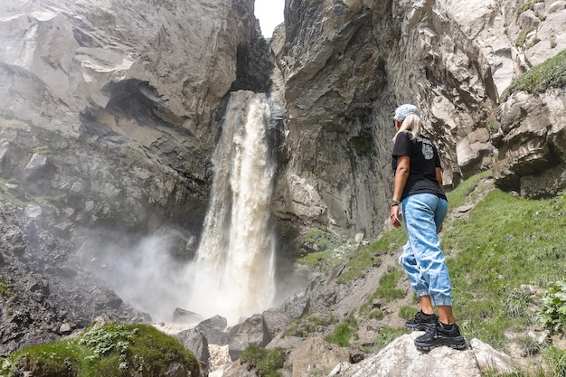 Una ragazza alla cascata Sultansu circondata dalle montagne del Caucaso vicino a Elbrus Jilysu Russia