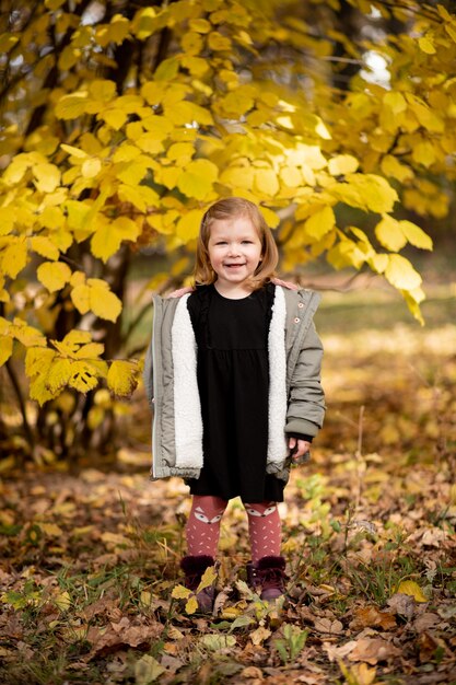 Una ragazza allegra sta nel parco d'autunno.