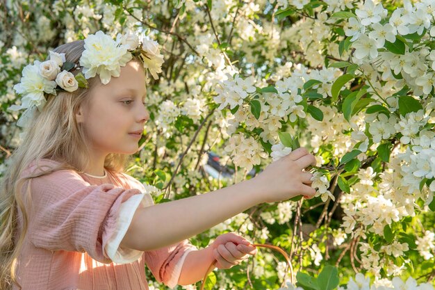 Una ragazza annusa una bella primavera bianca di melo nel mezzo della fioritura del melo