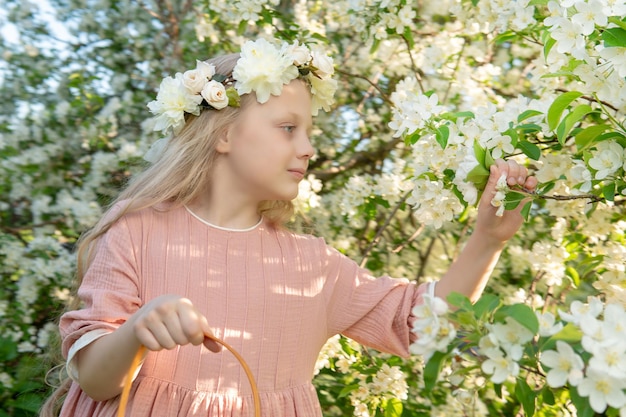 Una ragazza annusa una bella primavera bianca di melo nel mezzo della fioritura del melo