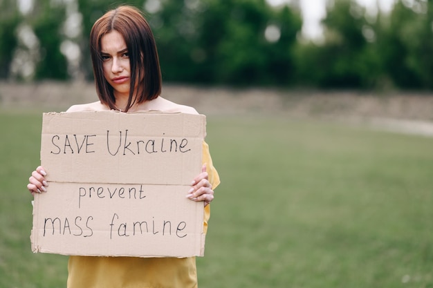 Una ragazza arrabbiata sta per strada con un cartello contro la guerra tra le mani La guerra della Russia contro l'Ucraina
