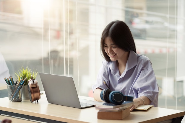 Una ragazza asiatica con le cuffie fa una lezione online usando una videochiamata al computer