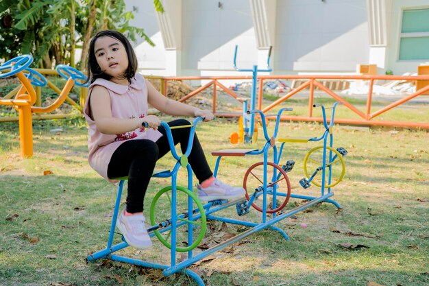 Una ragazza asiatica sta giocando in un parco giochi Sta andando in bicicletta da sola