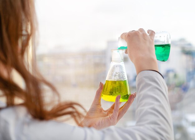 Una ragazza assistente di laboratorio mescola i reagenti in un laboratorio chimico
