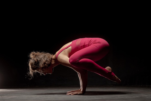 Una ragazza atletica in abiti sportivi luminosi sta facendo stretching su uno sfondo scuro Copia spazio