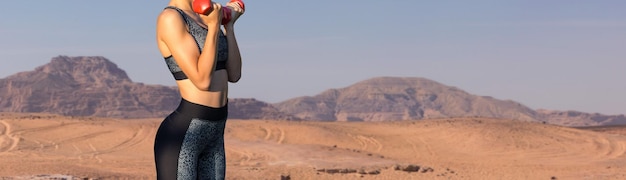 Una ragazza atletica magra si prende una pausa tra le lezioni sullo sfondo delle montagne al mattino presto