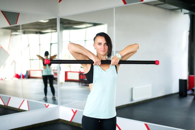 Una ragazza atletica si trova in palestra e mostra esercizi per il fitness di gruppo