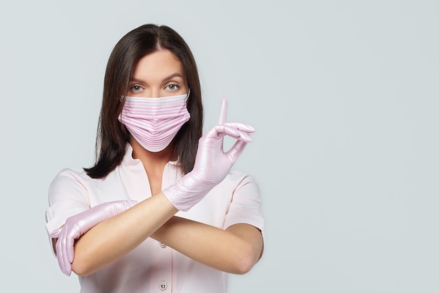 Una ragazza attraente in guanti rosa e una maschera protettiva