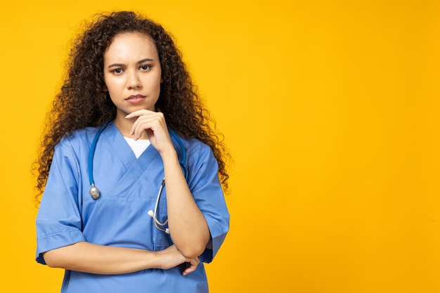 Una ragazza attraente in uniforme di infermiera blu su uno sfondo giallo