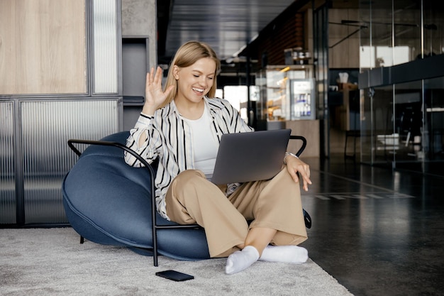 Una ragazza attraente sta lavorando su un computer portatile mentre era seduta su una sedia comoda