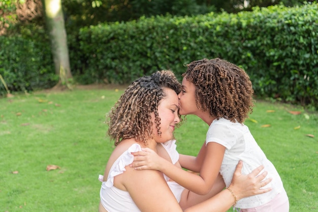 Una ragazza bacia sua madre sulla fronte all'aria aperta