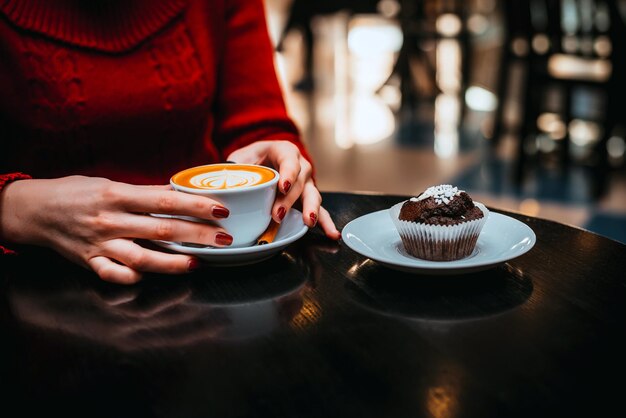 Una ragazza beve il caffè con il muffin