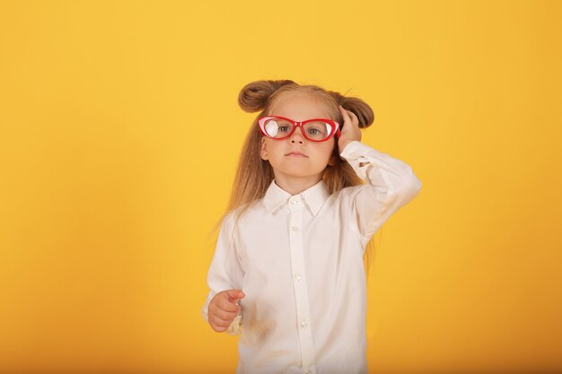 una ragazza bionda con gli occhiali una camicia bianca un prendisole grigio una scolaretta con gli occhiali su un giallo