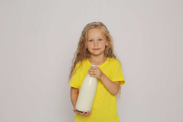 una ragazza bionda con una maglietta gialla con una bottiglia di vetro di una ragazza bionda con una T gialla tra le mani