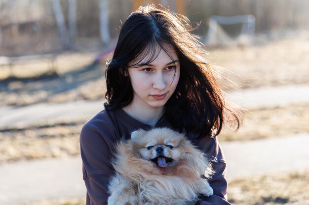 Una ragazza cammina con un cane nella ricreazione all'aperto del parco con un animale domestico un ritratto con un piccolo cucciolo