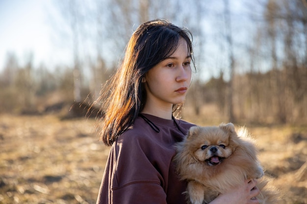 Una ragazza cammina con un cane nella ricreazione all'aperto del parco con un animale domestico un ritratto con un piccolo cucciolo