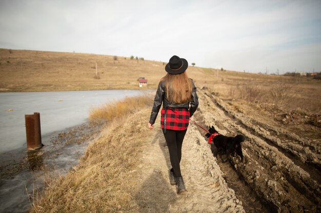 Una ragazza cammina con un cane sulla riva di un lago