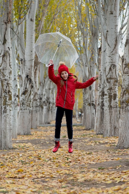 Una ragazza cammina e gioca con un ombrello trasparente nel parco Autumn Atmosther