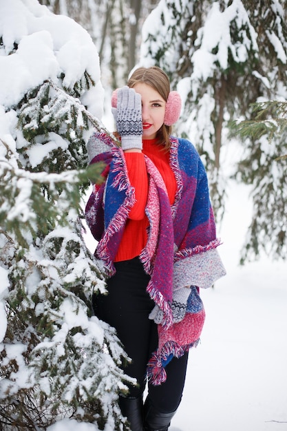 Una ragazza cammina in inverno dove tutti gli alberi di Natale sono coperti di neve Una sciarpa calda e luminosa
