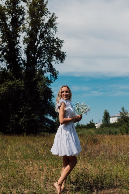 Una ragazza cammina in un campo in campagna con dei fiori in mano