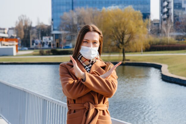 Una ragazza cammina in una maschera durante la pandemia e il coronovirus. Quarantena.